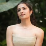 Rukmini Vasanth wearing an ivory Montsand tea-length gown against lush greenery