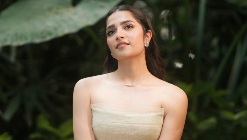 Rukmini Vasanth wearing an ivory Montsand tea-length gown against lush greenery