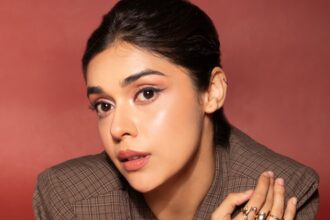 Eisha Singh wearing a brown plaid blazer and shorts in a retro-inspired fashion photoshoot