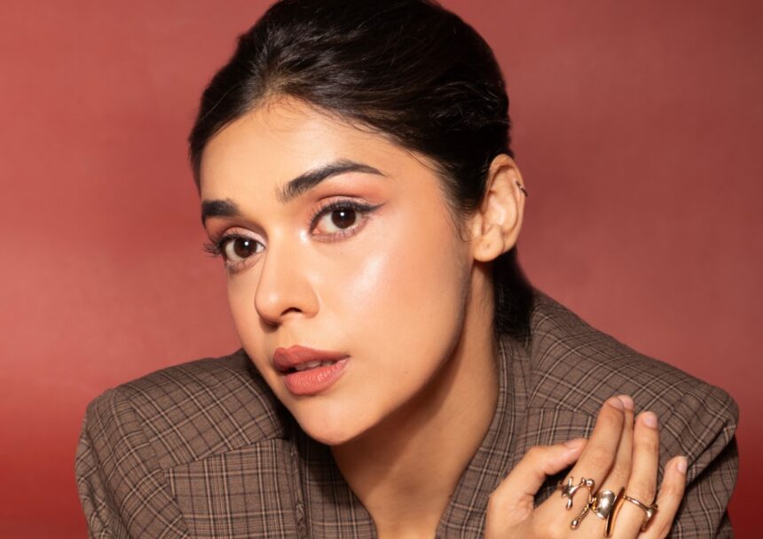 Eisha Singh wearing a brown plaid blazer and shorts in a retro-inspired fashion photoshoot
