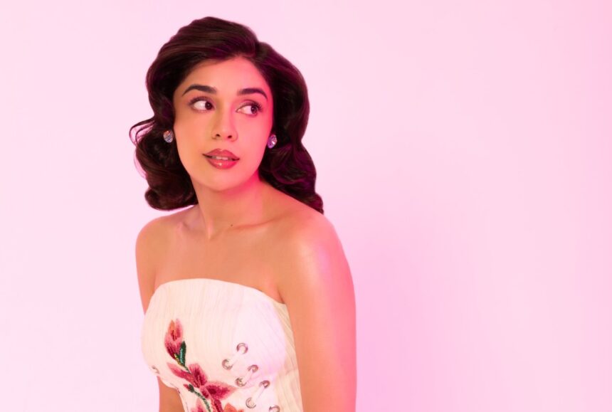Eisha Singh wearing an ivory corset and blush pink ruffled mini skirt in a retro Barbiecore photoshoot