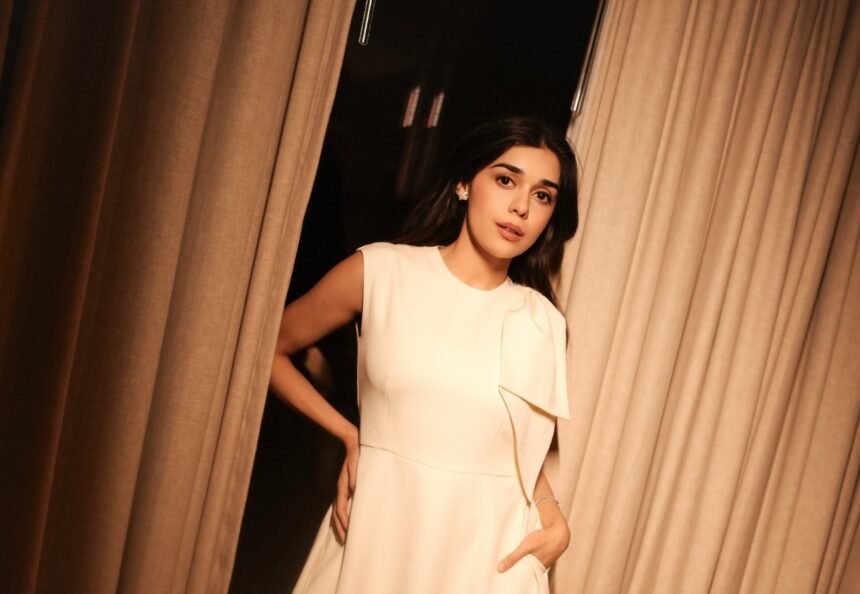 Rukmini Vasanth wearing an ivory draped dress in warm ambient lighting