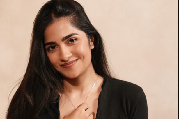 Rukmini Vasanth wearing a black top and relaxed light-wash jeans in a warm studio portrait