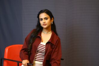 Ariyana Glory poses in a rust-maroon cropped jacket and wide-leg trousers