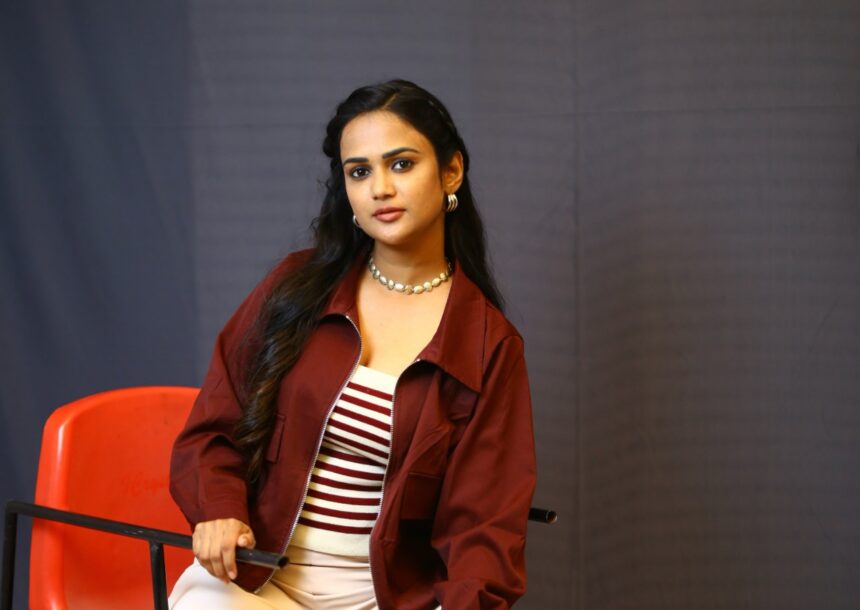 Ariyana Glory poses in a rust-maroon cropped jacket and wide-leg trousers
