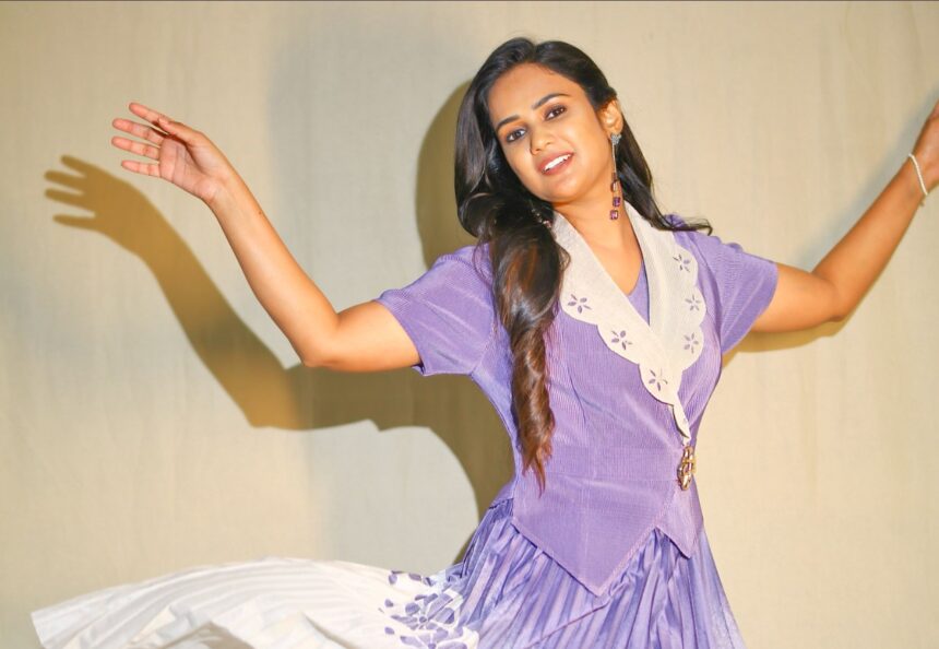 Ariyana Glory wearing a lilac pleated midi dress with a cream Peter Pan collar