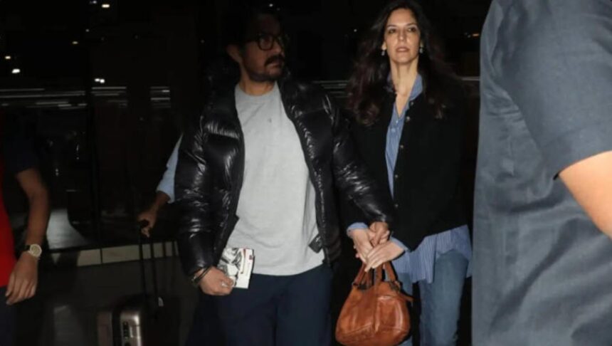 Hunterfly 2025 12 04 102923 Aamir Khan holds Gauri Spratt close as they walk hand-in-hand at Mumbai Airport.