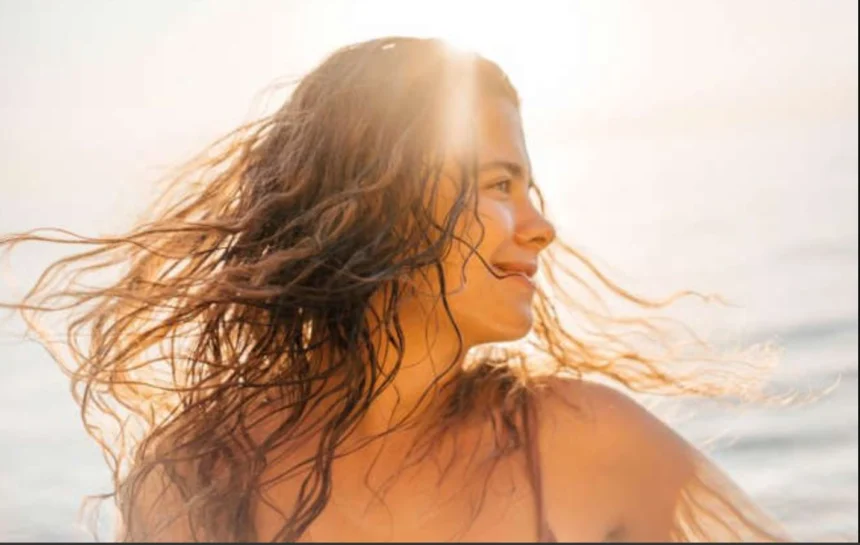 Woman with healthy shiny hair enjoying summer sunshine while following seasonal haircare tips