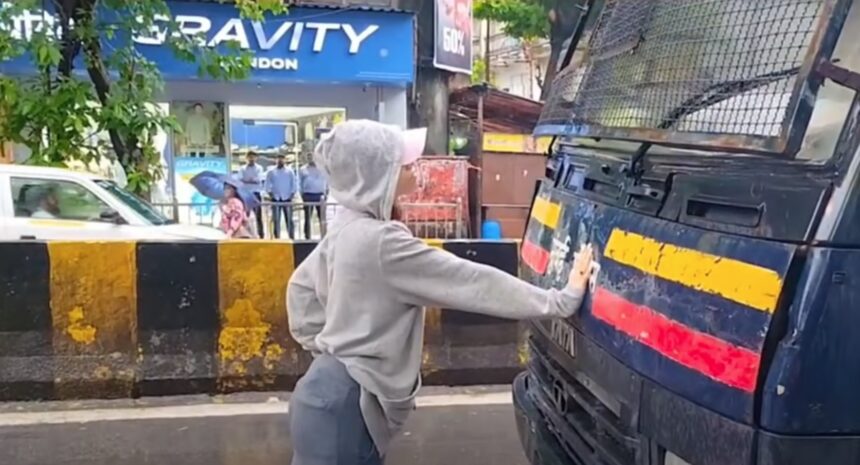 Woman stands in front of a police van during a student protest in Mumbai.