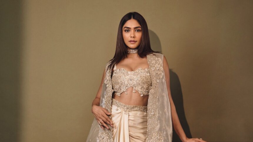 Mrunal Thakur wearing an ivory couture ensemble with an embellished corset, flowing embroidered cape and satin draped skirt.