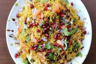 Crispy street-style potato chaat topped with sev, pomegranate seeds, coriander, and chutneys.