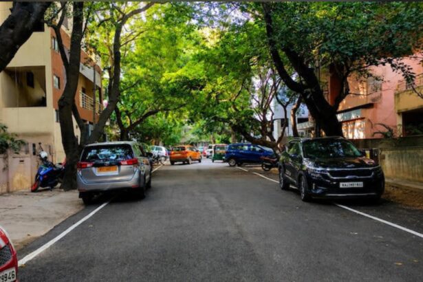 Evening view of Bengaluru's Indiranagar 100 Feet Road with tree-lined streets, cafés, restaurants and pedestrians.