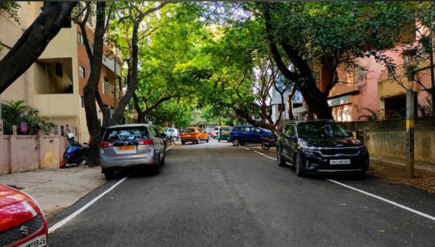 Evening view of Bengaluru's Indiranagar 100 Feet Road with tree-lined streets, cafés, restaurants and pedestrians.