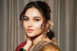Kayadu Lohar wearing a golden tissue-organza saree with a maroon blouse and traditional jewellery during a fashion photoshoot.