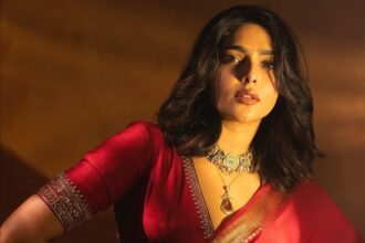 Aishwarya Lekshmi wearing a crimson-red embroidered saree with traditional gold temple jewellery during a fashion photoshoot.