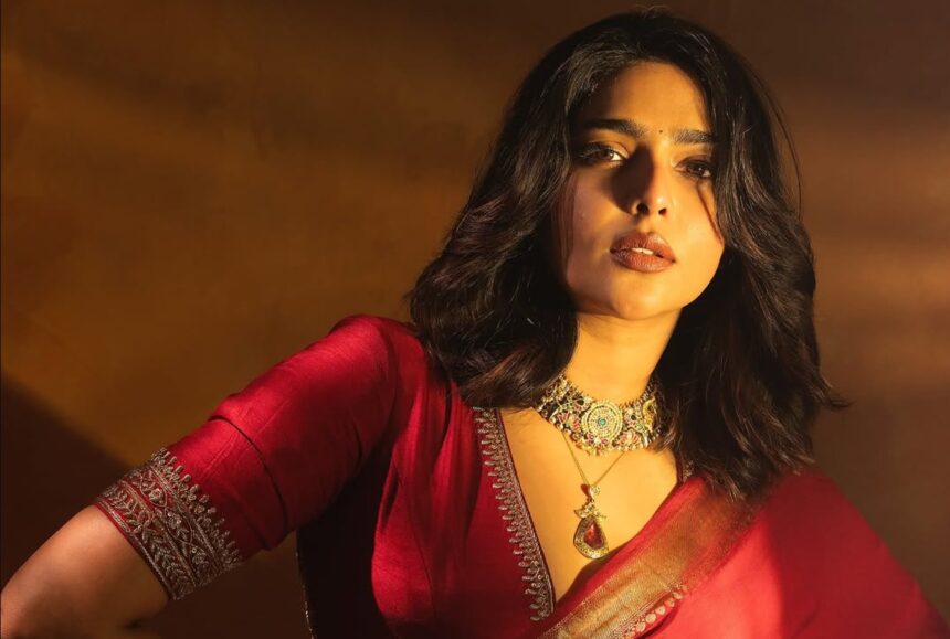 Hunterfly 2026 08 07 193156 Aishwarya Lekshmi wearing a crimson-red embroidered saree with traditional gold temple jewellery during a fashion photoshoot.