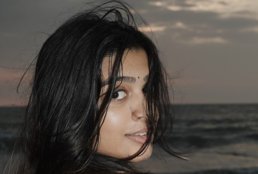 Ananthika Sanilkumar in a black and white checkered dress at the beach during sunset