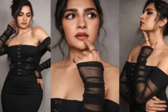 Rukmini Vasanth poses in a sleek black fitted dress with shoulder-drop detailing