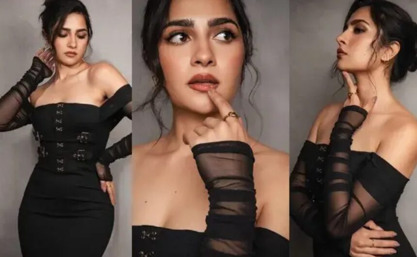 Rukmini Vasanth poses in a sleek black fitted dress with shoulder-drop detailing