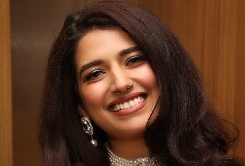 Rasha Kirmani wearing a shimmering blue outfit with a pearl choker