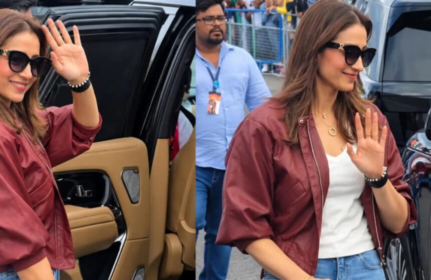 Trisha Krishnan wearing a maroon bomber jacket and light-wash jeans at Silverstone
