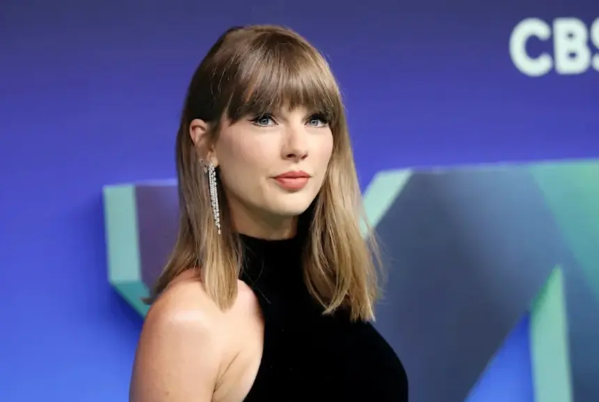 Taylor Swift with curly blonde hair wearing a maroon sweater