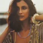 Diksha Singh poses in a gold-patterned kaftan over beachwear in coastal photographs.